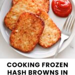 A plate with four cooked hash browns and a serving of ketchup, with a fork on the side. Text reads: "Cooking frozen hash browns in an air fryer.