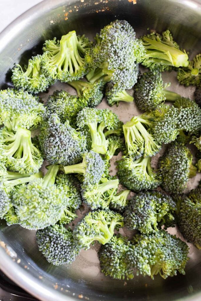Fresh broccoli florets in a stainless steel pot, ready for cooking.