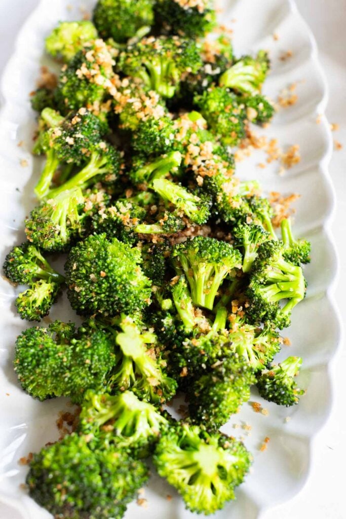 A plate of sauteed parmesan broccoli florets on a white serving dish.