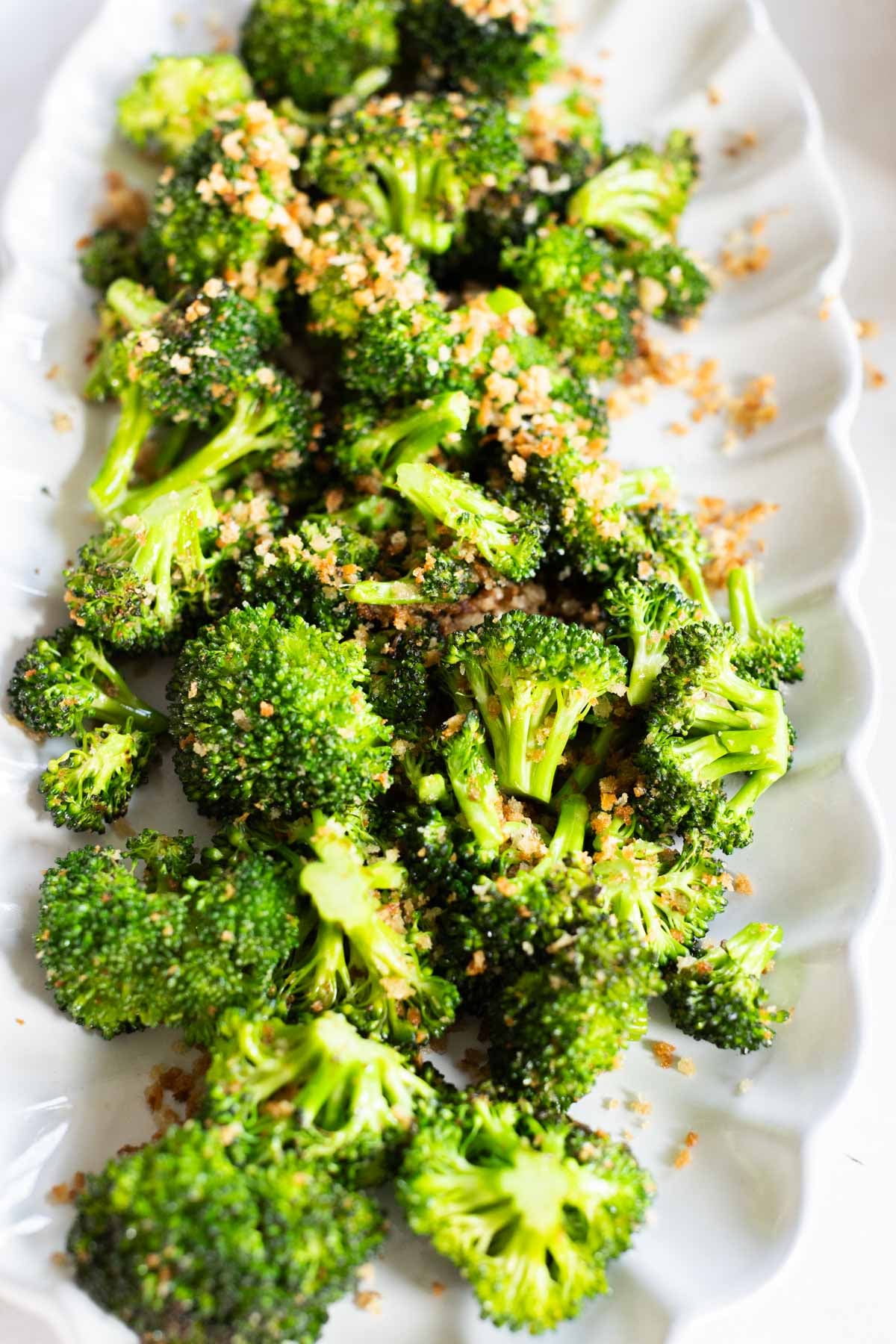 A plate of sauteed parmesan broccoli florets on a white serving dish.