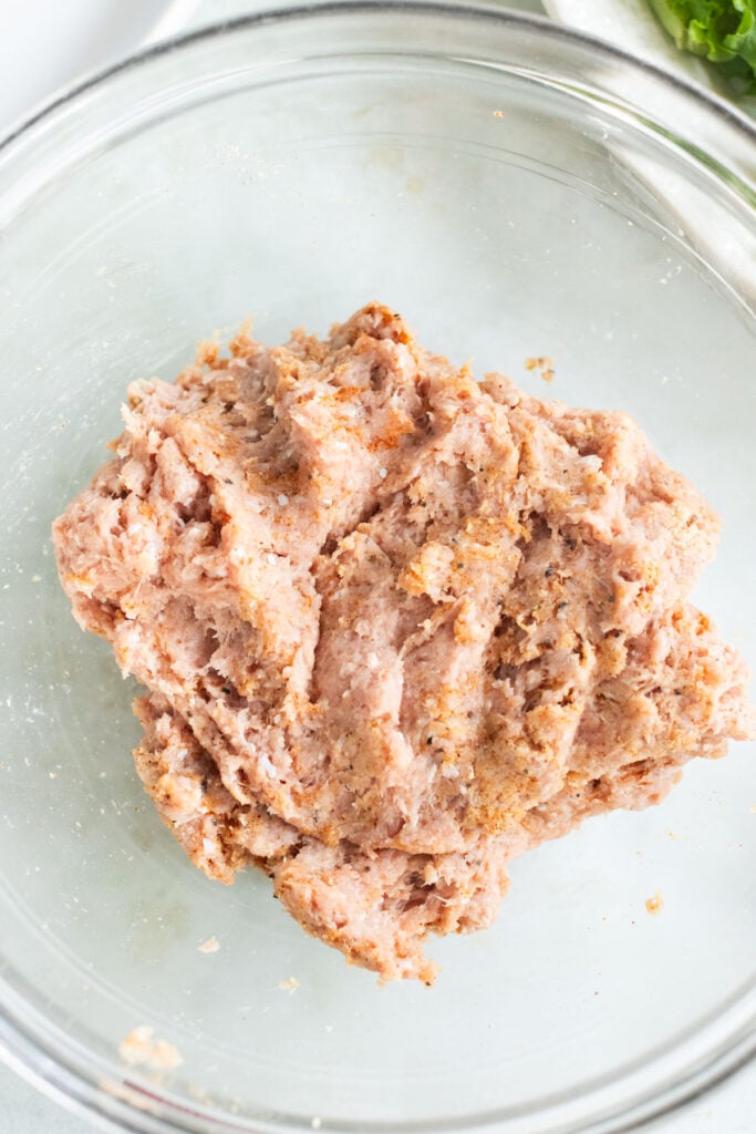 Ground meat mixture in a clear glass bowl, viewed from above.