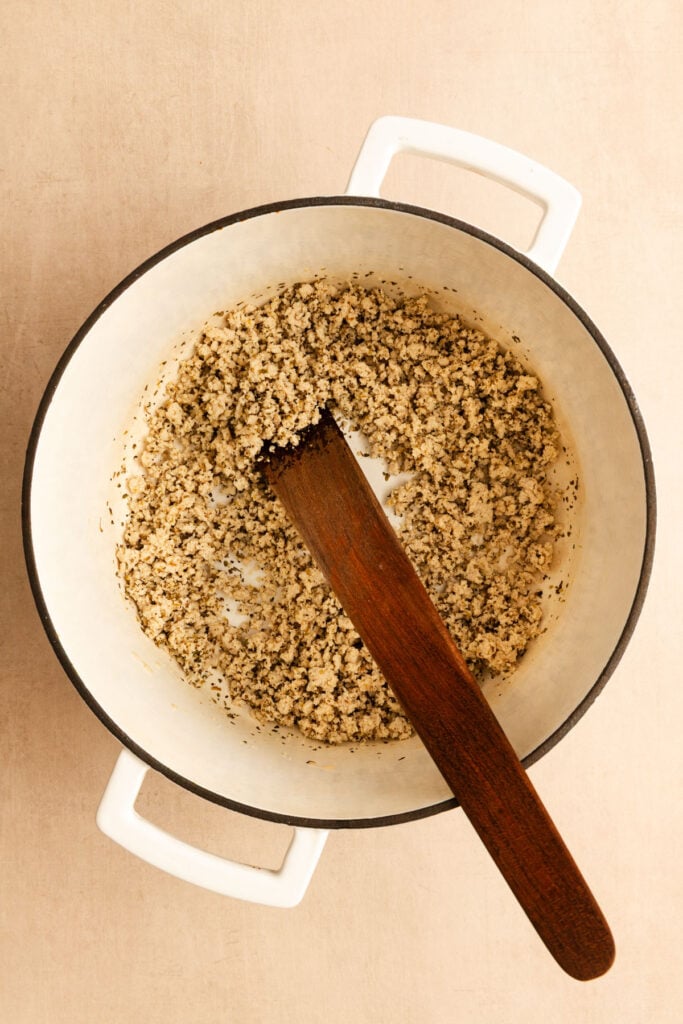 Ground turkey being cooked in a large Dutch oven, viewed from overhead.