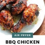 Four barbecued chicken drumsticks on a white plate, charred and glazed, with the text “AIR FRYER BBQ CHICKEN DRUMSTICKS cookathomemom” below.
