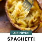 A fork holds strands of cooked spaghetti squash above a halved squash shell, with text overlay reading "Air Fryer Spaghetti Squash – cook at home mom.