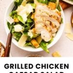 A bowl of grilled chicken Caesar salad with romaine lettuce, croutons, Parmesan cheese, and Caesar dressing, viewed from above.