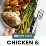 A plate with baked chicken breast, roasted potatoes, and asparagus spears beside a fork and knife. Text reads: "Sheet Pan Chicken & Potatoes cookathomemom.