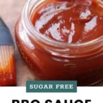 An open jar of BBQ sauce with a basting brush beside it. Text on image reads: "Sugar Free BBQ Sauce, cook at home mom.