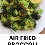 A plate of air fried broccoli with two lemon wedges and a spoon on the side. Text below reads, “Air Fried Broccoli from Fresh or Frozen. Cook at Home Mom.”.
