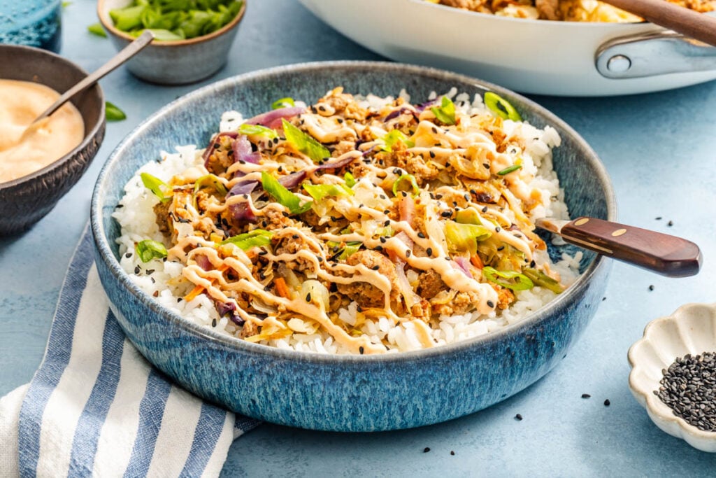 A deconstructed egg roll in a bowl served over fluffy white rice.