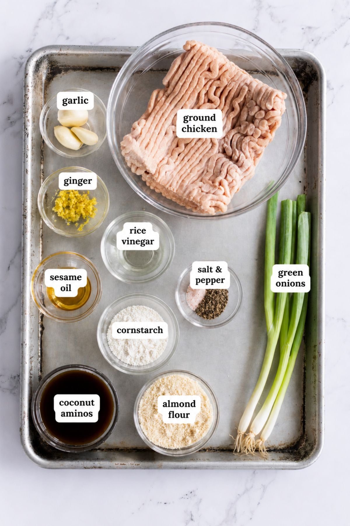 A tray holds bowls of ground chicken, garlic, ginger, rice vinegar, sesame oil, salt and pepper, cornstarch, coconut aminos, almond flour, and whole green onions—everything you need to create flavorful teriyaki meatballs.
